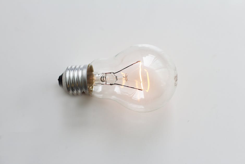 A close-up of an illuminated incandescent light bulb against a white background.