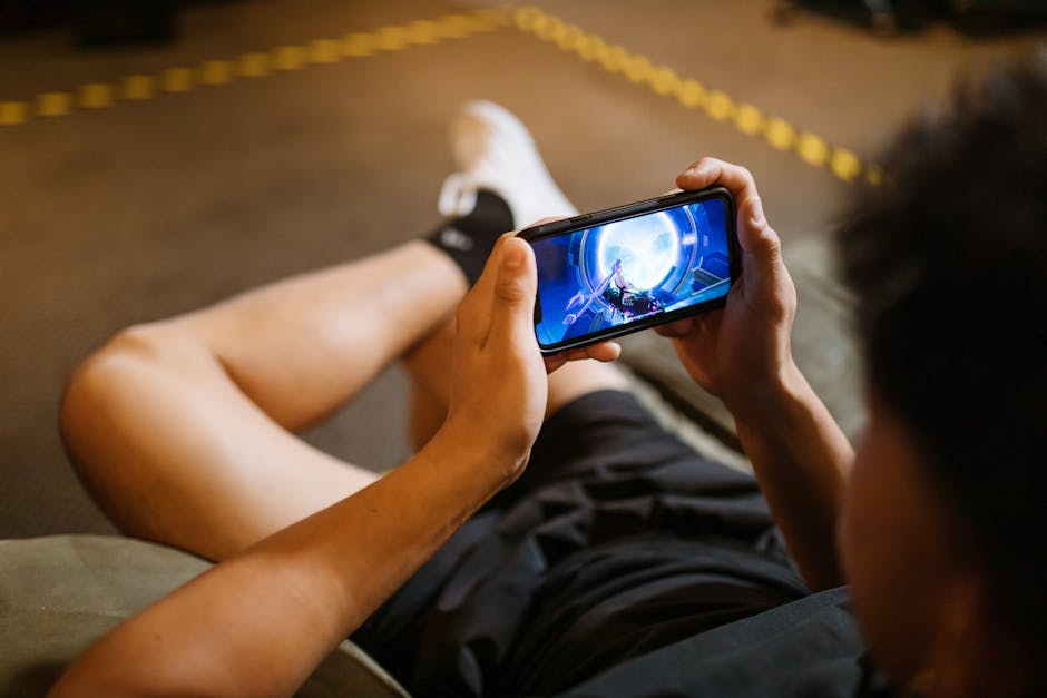 Man playing a video game on a smartphone while sitting comfortably indoors.